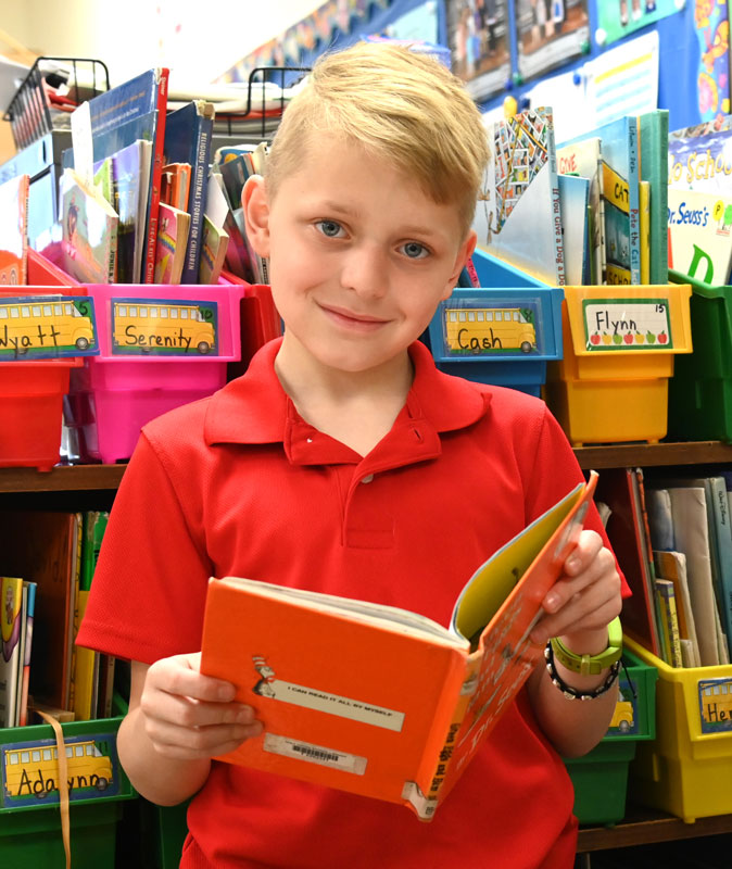 Student in uniform with book in classroom.