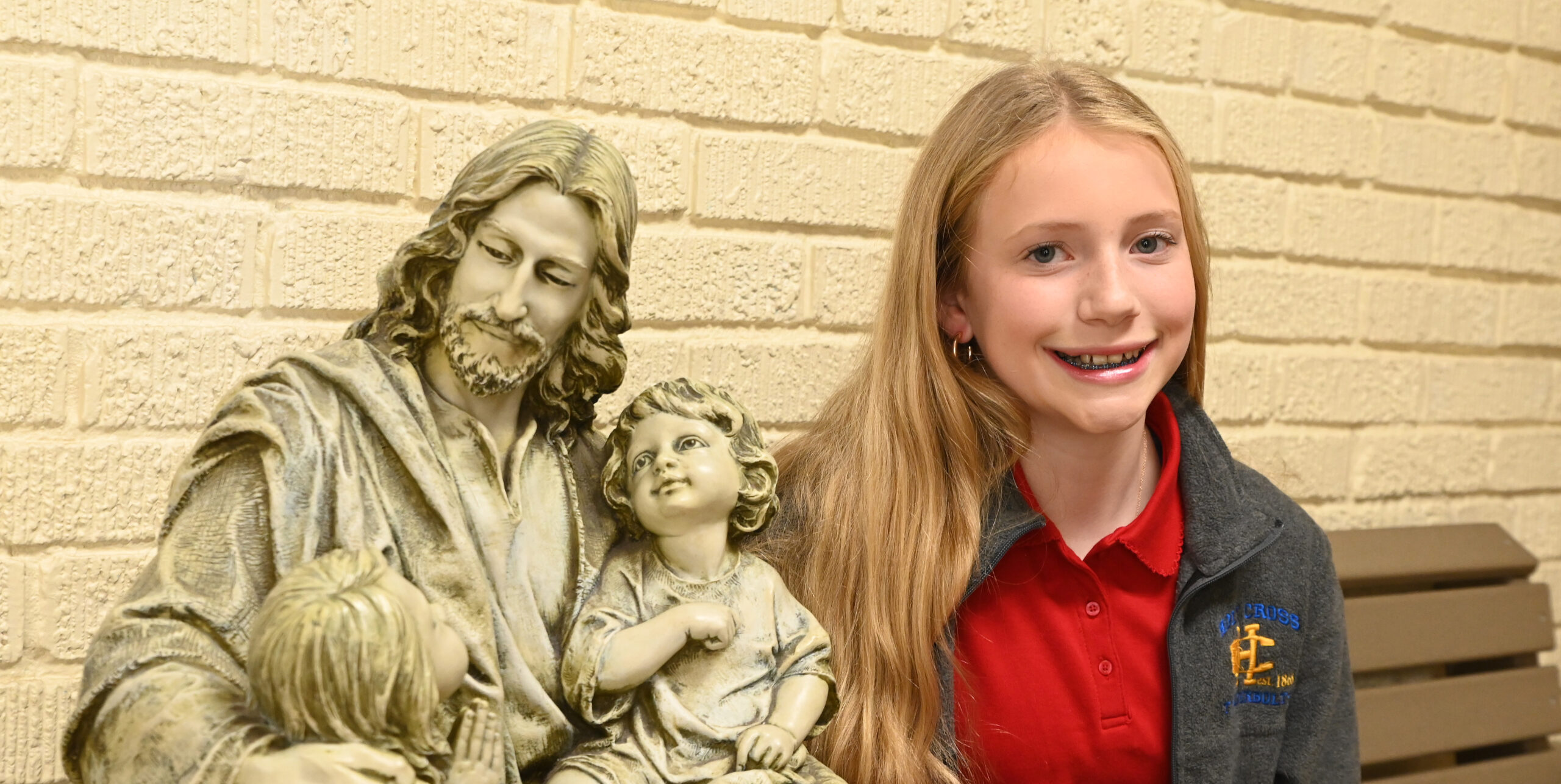 Student sits next to statue of Jesus at Holy Cross School which is located near Wequiock Falls.